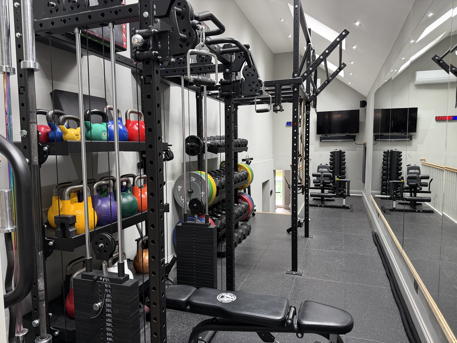 The private Harrow gym, with cable machines, colourful kettlebells, dumbbells and a clear mirrored training area